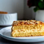 Slice of German Bee Sting Cake with cream filling and almond topping